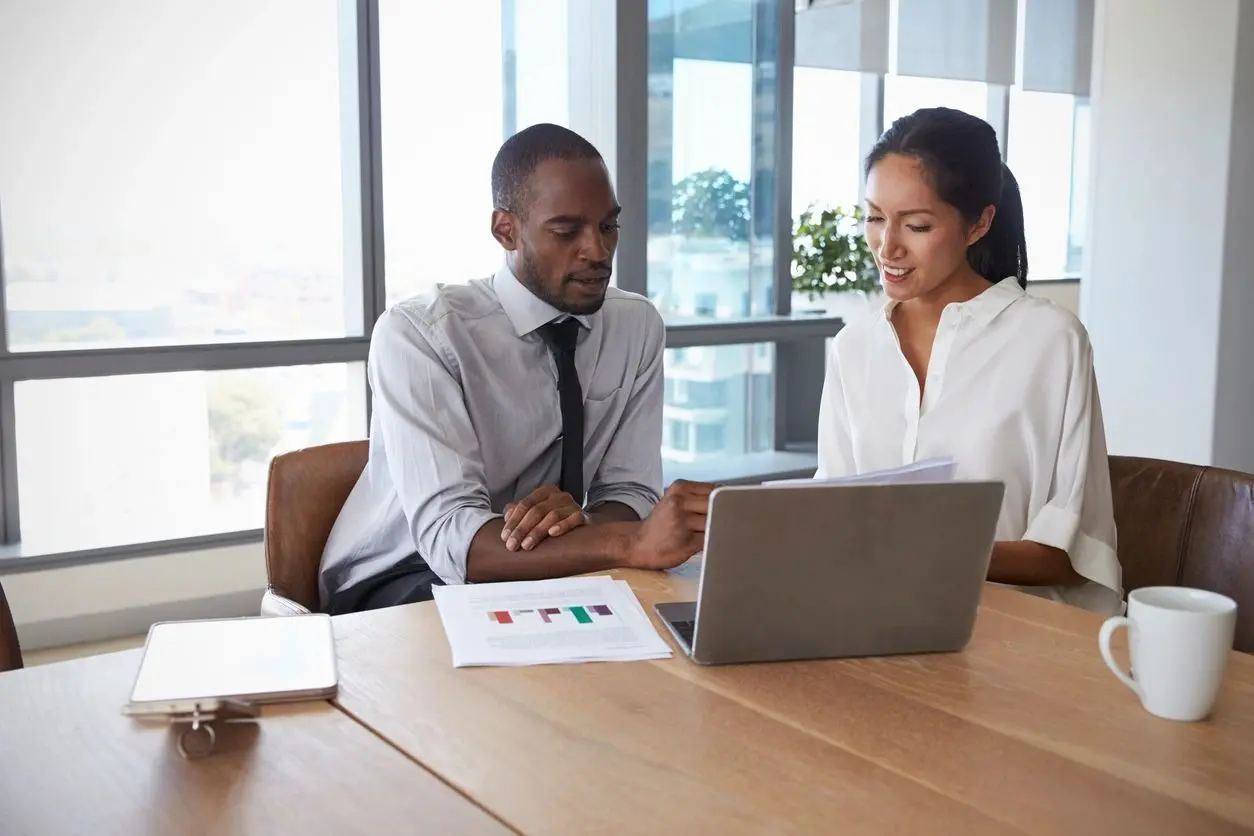 Two colleagues discussing data charts in a modern office.
